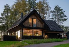 Темный деревянный дом, растворяющийся в норвежском лесу